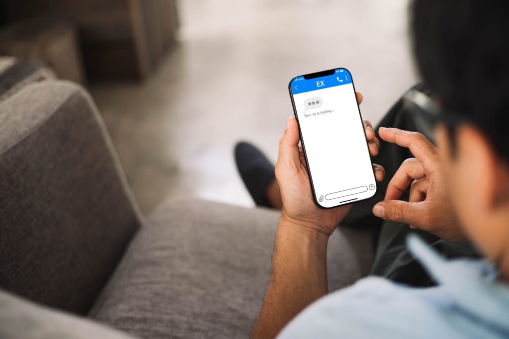 A man staring at his phone while the text “Typing…” disappears over and over again, symbolizing the frustration of waiting for a response that never comes